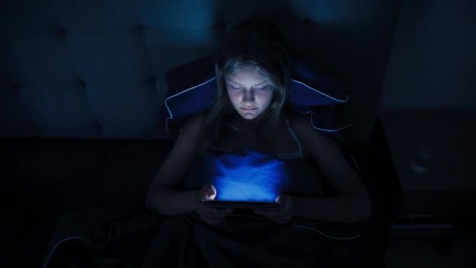 使用平板电脑设备躺在床上的女人