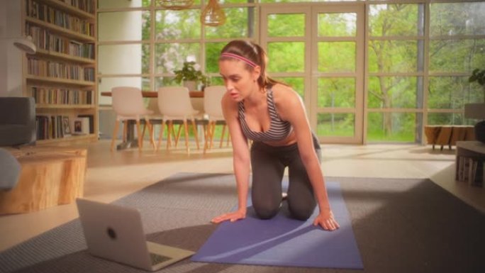 女运动员准备瑜伽垫和笔记本电脑进行锻炼。家庭锻炼