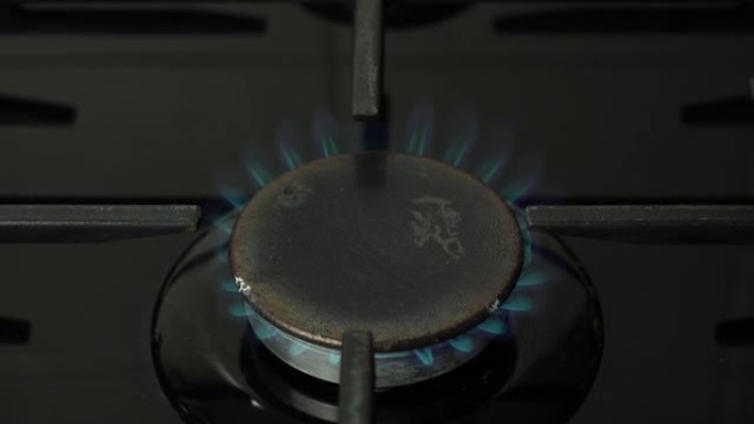 带点燃火的厨房燃烧器燃气灶。燃气灶燃烧蓝色火焰。