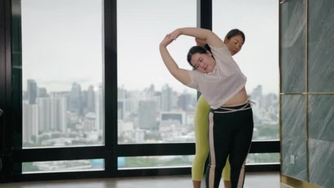 培训师正在教肥胖女性如何正确地做瑜伽。加强身体强壮的能力