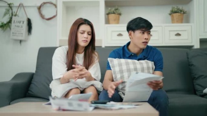亚洲年轻已婚夫妇在家检查文件，对超支感到困惑