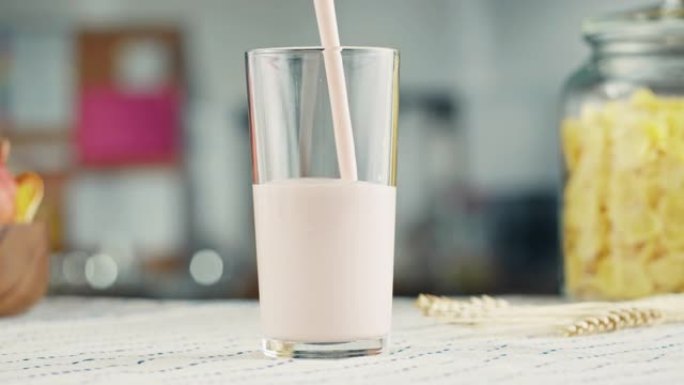 将酸奶倒入玻璃杯特写镜头。玻璃配开菲尔或牛奶，奶制品概念。早上喝新鲜的无乳糖牛奶。