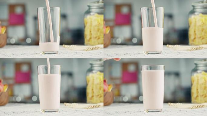 将酸奶倒入玻璃杯特写镜头。玻璃配开菲尔或牛奶，奶制品概念。早上喝新鲜的无乳糖牛奶。
