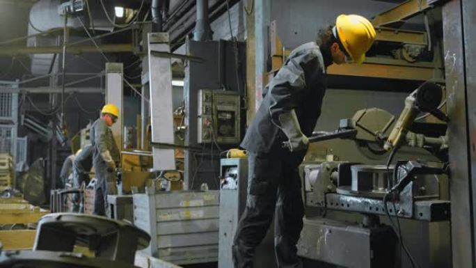 铸造厂的DS男工人通过衬里在金属铸件上工作