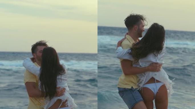 海滩上浪漫的旋转。充满爱心的男朋友在空中举起女友并在垂直视频中旋转