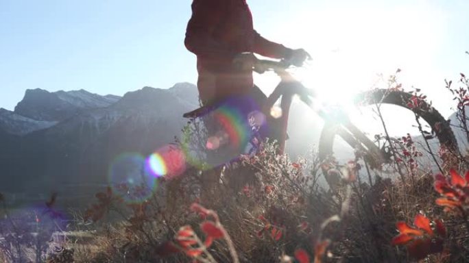山地车手将自行车推上陡峭的小路，远处的山脉