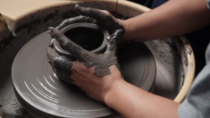 匿名人士在陶艺工作室使用陶轮和雕刻粘土。年轻人为产品铸造粘土。教育、商业、艺术天赋和创意手工制作的概