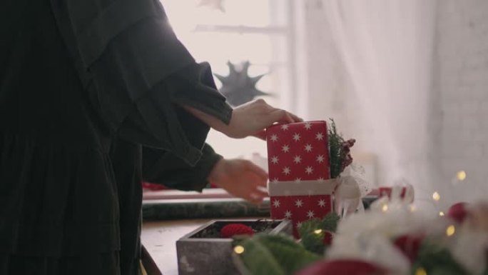 一名年轻女子用红纸包装圣诞礼物，并用丝带绑上。
