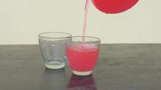 西瓜汁从水罐倒入两杯中，健康的红色西瓜饮料带有复制空间。