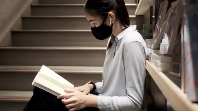 亚洲女人戴防护面膜布看书。