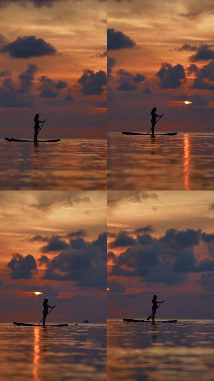 日落时年轻女子划桨