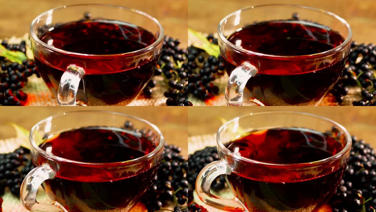 在转盘上的玻璃杯中特写天然红莓茶。黑接骨木浆果中的浆果茶。从浆果中挤出的顺势疗法果汁