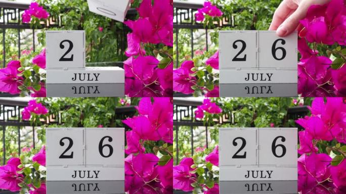 一个木制日历，有一个重要的活动，7月26日在一张有芙蓉花的桌子上，女人的手在日历上设定了日期。将日历