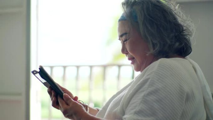 高级妇女在家中的数字平板电脑上进行视频通话。