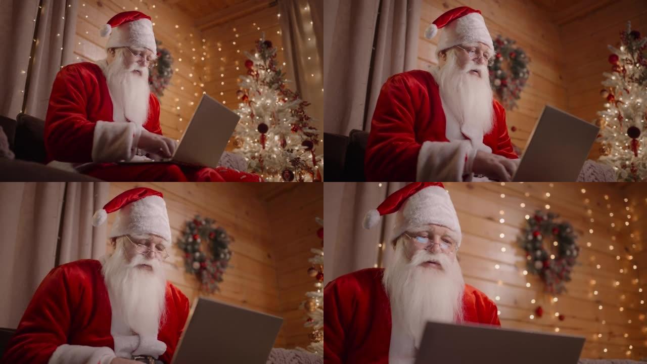 真正的圣诞老人仰视图坐在带眼镜的沙发上的笔记本电脑上，并在笔记本电脑上工作。圣诞节和平安夜Sonta