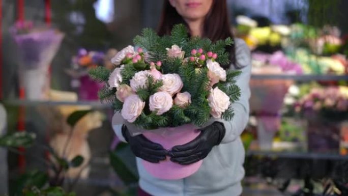 前视图无法辨认的女人站在花店里，将美丽的花束伸向相机。苗条的年轻高加索女性花店在室内炫耀花朵。