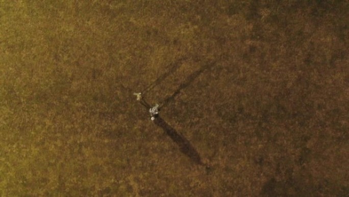空中无人机拍摄了两个人在夜间在田野里踢足球的镜头