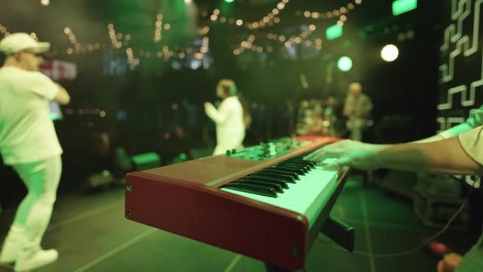 indiepop和jazz funk音乐乐队在现代音乐厅的舞台上表演，合成器和男性手的特写镜头