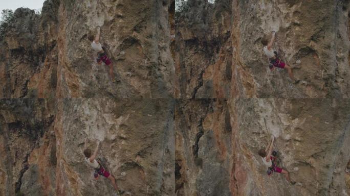 空中无人机拍摄了一名女子攀爬在红色岩壁上的岩石
