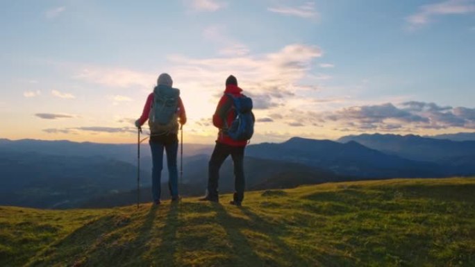 SLO MO男女徒步旅行者站在山顶欣赏日落