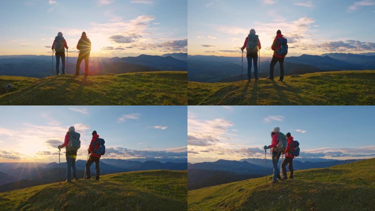 SLO MO男女徒步旅行者站在山顶欣赏日落