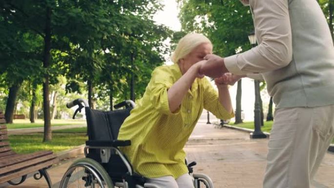 丈夫帮助残疾妻子从轮椅上站起来，照顾