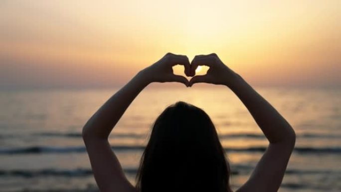 海滩上的年轻女子用手做心形