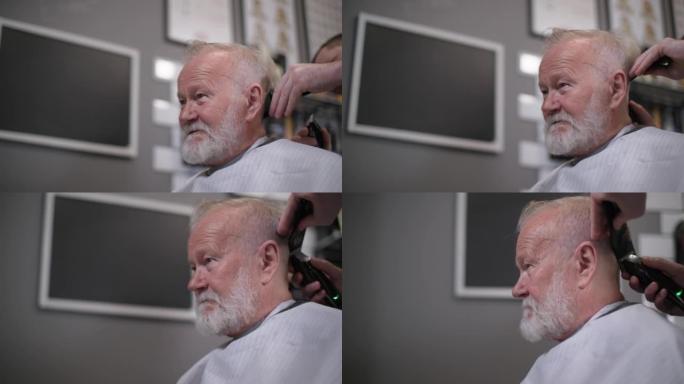 一位时髦的退休老人在一家时尚男士理发沙龙的专业理发师那里剪他的头发和胡子