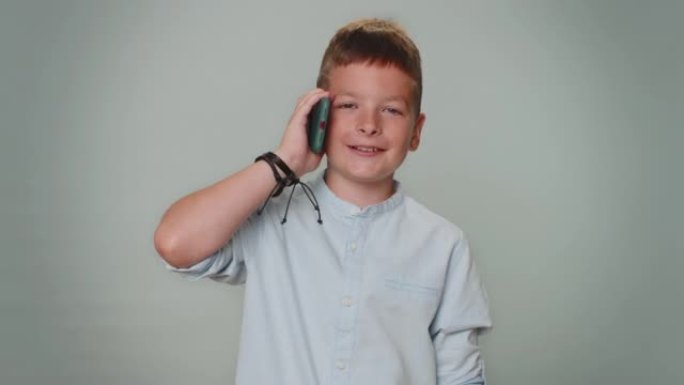 蹒跚学步的小男孩使用智能手机与朋友讲述好消息进行愉快的移动对话