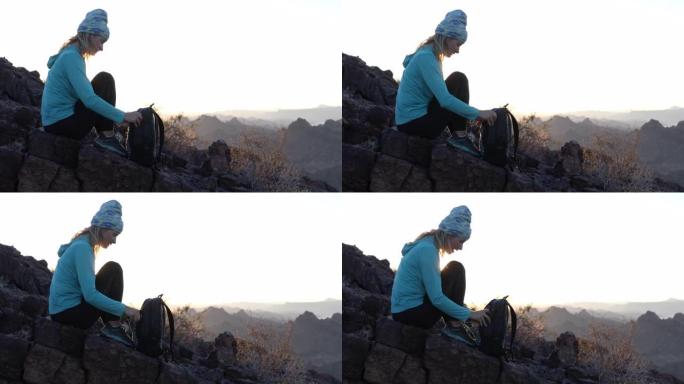 女徒步旅行者在山顶上放松，背着背包