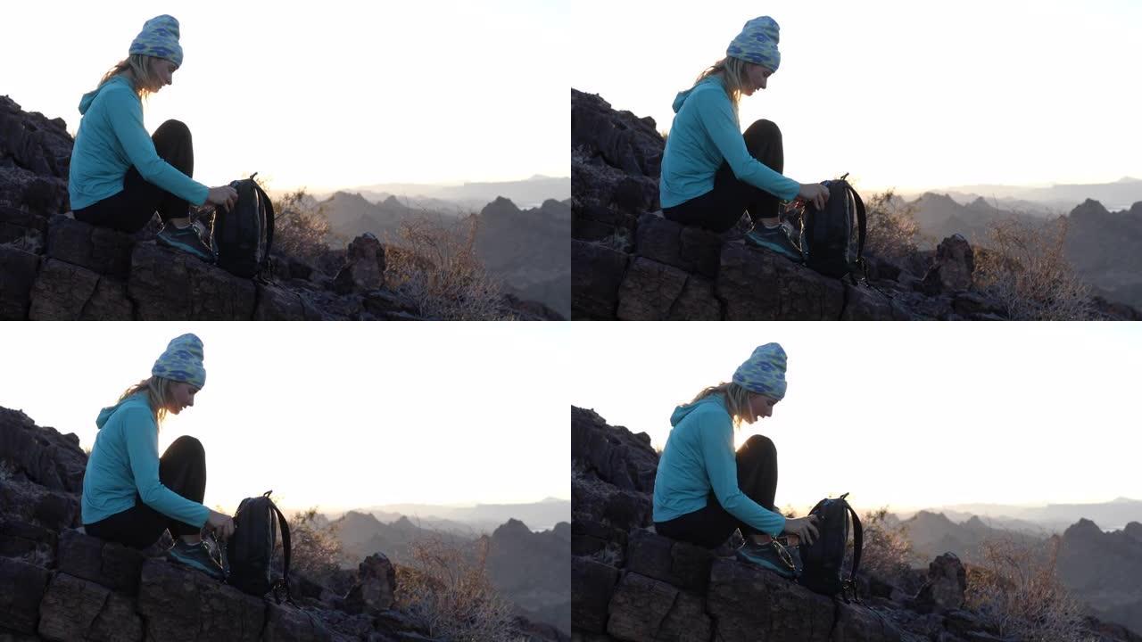女徒步旅行者在山顶上放松，背着背包