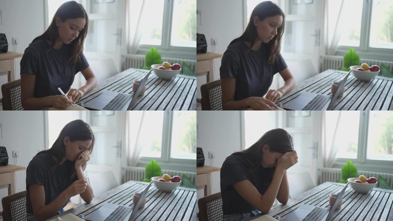 年轻女子沮丧地坐在桌子旁，用电脑
