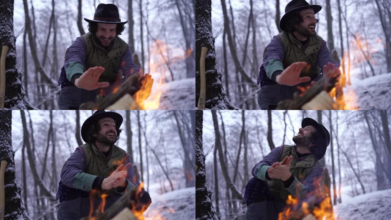 男子坐在篝火旁，在火焰上温暖双手
