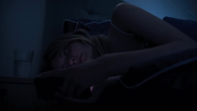 躺在床上的女人因失眠而无法入睡。检查电话