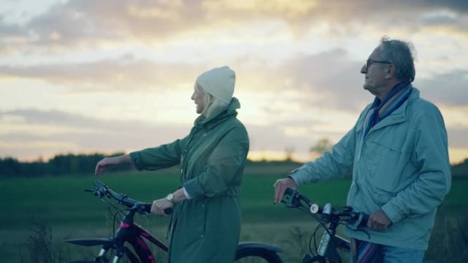 老年夫妇在外面骑自行车。步行回家，一起骑自行车