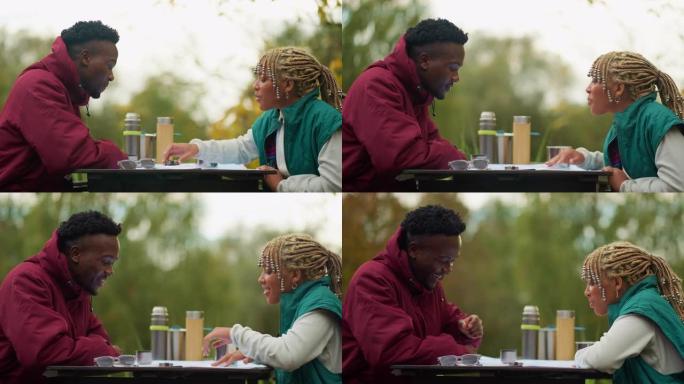 非洲族裔少年夫妇看着地图和指南针，从北欧人在公园餐桌上散步休息。