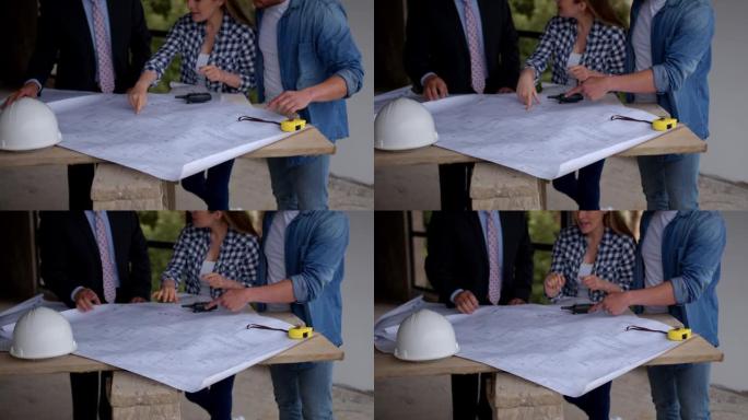 房地产开发商和夫妇在简易桌子上看着新房建筑工地的蓝图