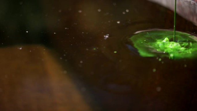 将绿色液体倒入大桶水中的细节镜头