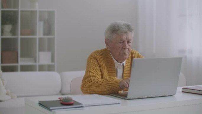 高级成熟的老年妇女在键盘上输入消息，在笔记本电脑上进行在线网络研讨会远程工作或在家进行社交远程学习。
