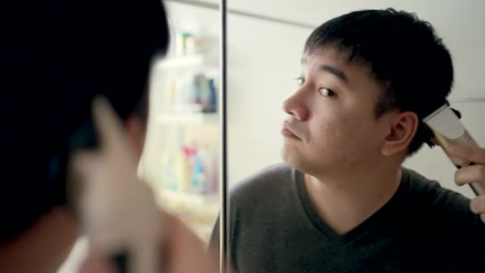 亚洲男人在房子里剪头发，自己动手。