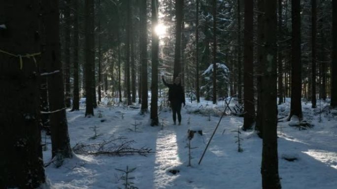 女人在日落时穿过白雪皑皑的森林