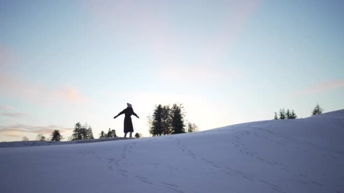 女人在日落后的冬天在山坡上跳舞