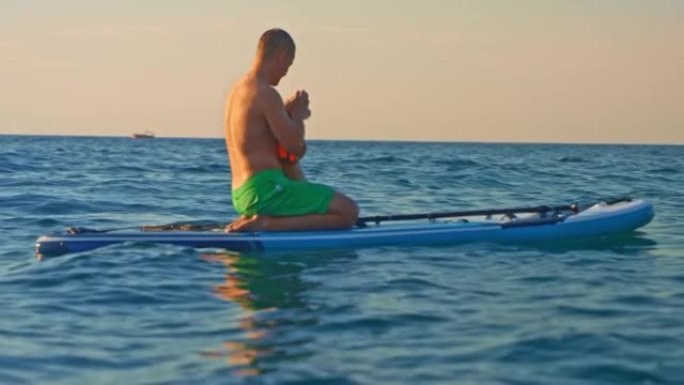 SLO MO Man坐在海上的桨板上抚摸他的小狗