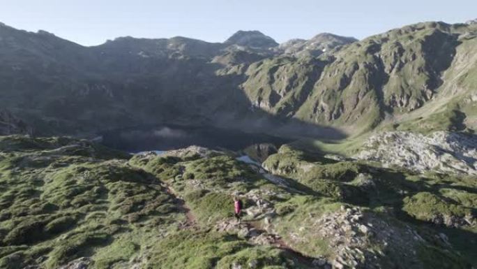 空中无人机拍摄的一名年轻女子在山区崎terrain的地形中徒步旅行