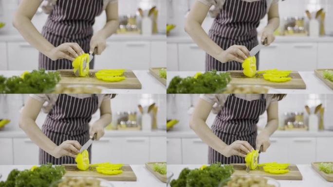 女人用刀将黄色甜椒切成薄片