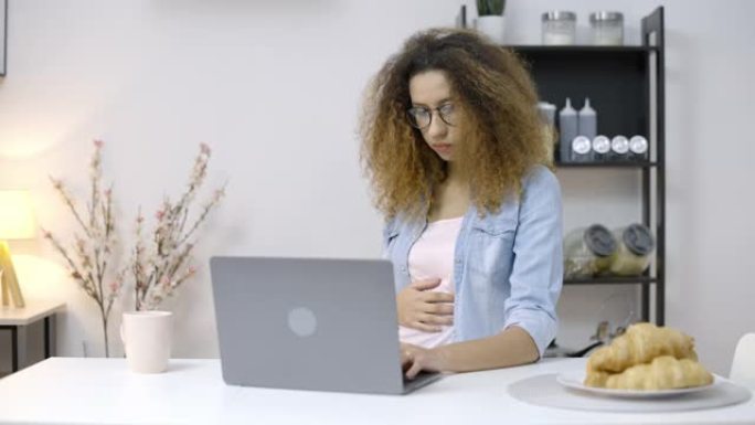 怀孕的混血儿女性感觉恶心，在笔记本电脑上工作，晨吐