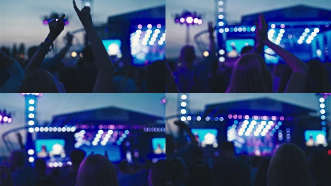 人群在音乐节上欢呼。专注于举手跳舞的女人