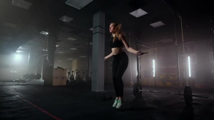 慢动作: 年轻女子跳绳。女人在健身房跳来跳去，这是她锻炼的一部分，坚定的女人专注于