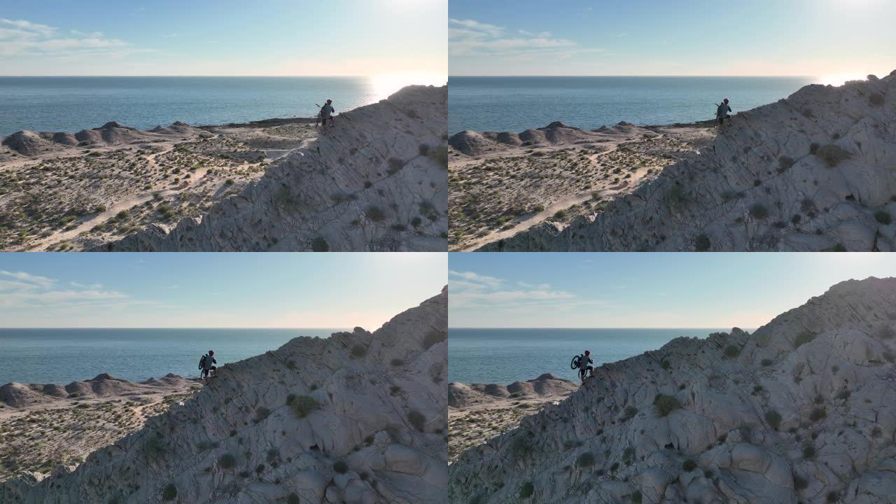 男子将山地自行车抬上岩脊的鸟瞰图