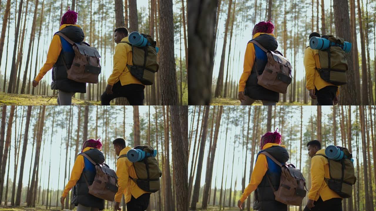 迷人的现代游客黑人夫妇徒步攀登森林山丘，看着远处的动物。自然公园。娱乐概念。慢动作行走
